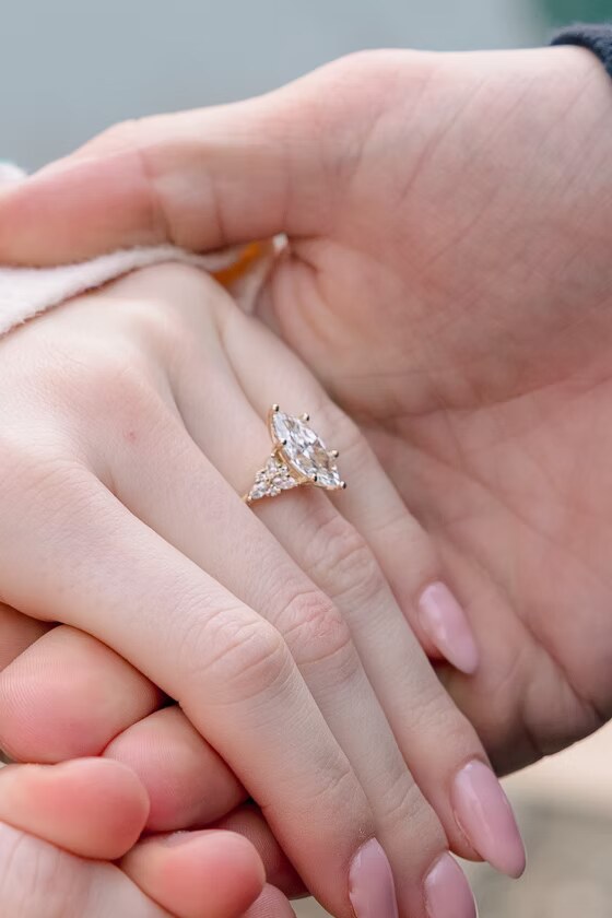 Two people holding hands, engagement ring visible